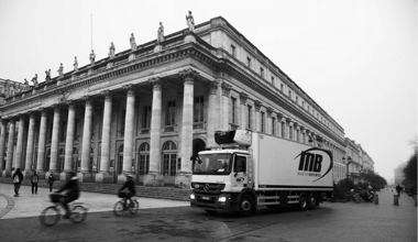 Martin Brower 18-wheeler truck driving in front of a city building.