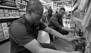 Two Reyes Holdings team members sorting and storing Reyes Coca-Cola products on shelves.