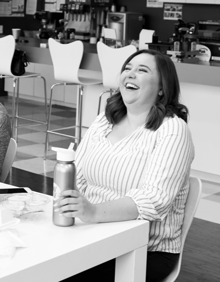 A Reyes Holdings team member sitting down in cafeteria and laughing.