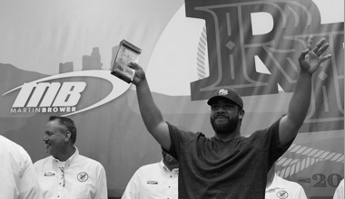 Image of a a Reyes Holdings team member celebrating his award with a group of leaders in the background.