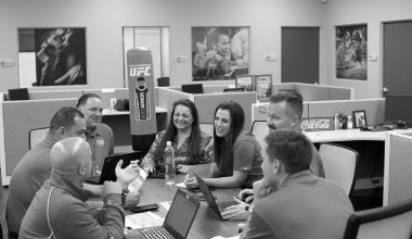 A group of Reyes Holdings Team members huddling at a conference table.