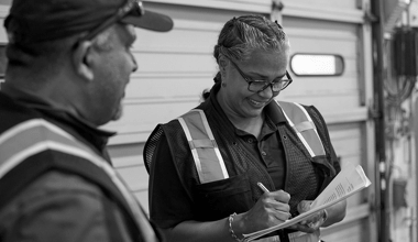Two Reyes Holdings team members working together and reviewing a checklist.