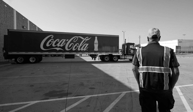 An image of a Reyes Holdings team members looking at an 18-wheeler Reyes Coca-Cola truck.